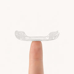 A Heration night guard balanced on a fingertip, showing how slim it is